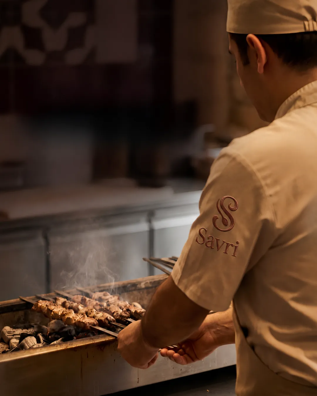 A Savri chef grilling kebabs over live coals